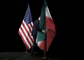 FILE PHOTO: A staff member removes the Iranian flag from the stage after a group picture with foreign ministers and representatives of the U.S., Iran, China, Russia, Britain, Germany, France and the European Union during Iran nuclear talks at the Vienna International Center in Vienna, Austria, July 14, 2015.  REUTERS/Carlos Barria/File Photo - RC13F9DDA150