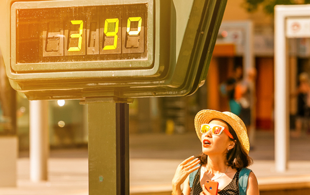 Woman suffers from heat and sunstroke outside in hot weather on the background of a street thermometer showing 39 degrees Celsius