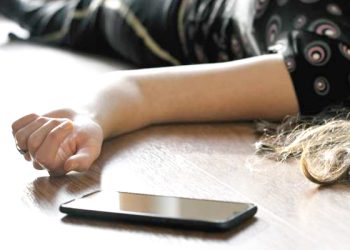 Woman lying on the floor at home, phone fallen near her hand. Crime scene, epilepsy, unconsciousness, faint, stroke, accident or other health problem.